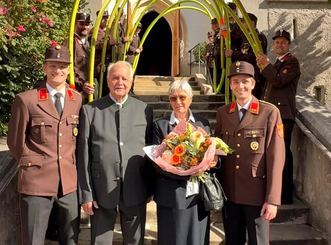 Josef Zinner und seine Frau feiern die Eiserne Hochzeit unter festlichen Bögen mit Freunden und Familie.